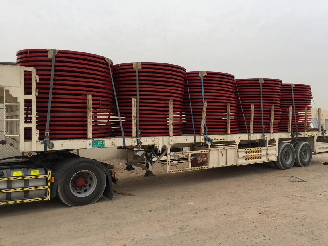 Red steel drum flanges loaded on a flatbed trailer for delivery